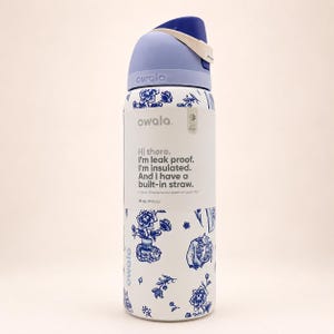 May include: A white Owala water bottle with a blue floral pattern and a light blue lid. The label reads: Hi there. I'm leak proof. I'm insulated. And I have a built-in straw. I know. Where have I been all your life? 32 oz. (945 mL).