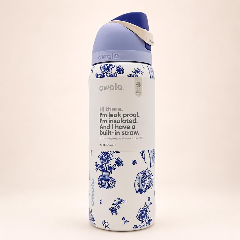 May include: A white Owala water bottle with a blue floral pattern and a light blue lid. The label reads: Hi there. I'm leak proof. I'm insulated. And I have a built-in straw. I know. Where have I been all your life? 32 oz. (945 mL).