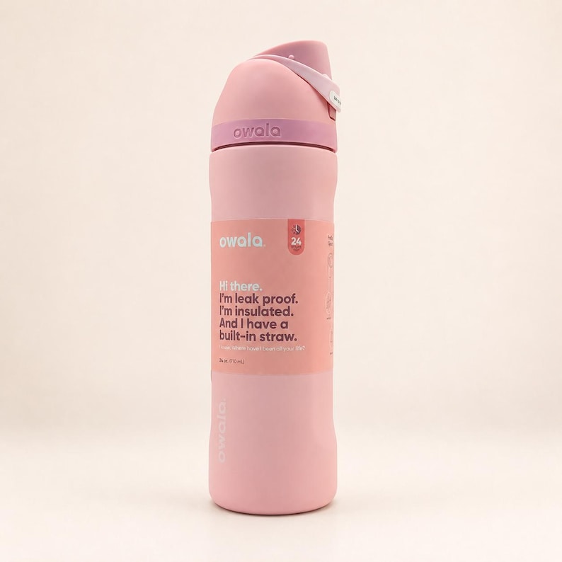 May include: A light pink insulated water bottle with a matching lid and a built-in straw. The label reads: Owala, Hi there. I'm leak proof. I'm insulated. And I have a built-in straw. 24 oz. (710 ml). The bottle features a carry loop and branding.