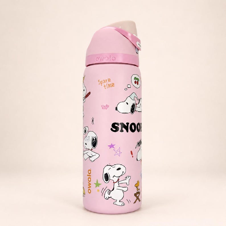 May include: A light pink Owala water bottle featuring Snoopy graphics, the text "SNOOPY" in bold black letters, and the phrase "Spare time" in orange. The bottle has a matching pink lid with a beige push-button mechanism and a carry handle.