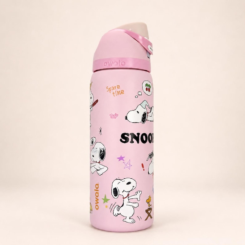 Pu&ograve; includere: Una borraccia Owala rosa chiaro con grafiche di Snoopy, il testo "SNOOPY" in grassetto nero e la frase "Spare time" in arancione. La bottiglia presenta un tappo rosa abbinato con un meccanismo a pulsante beige e una maniglia per il trasporto.