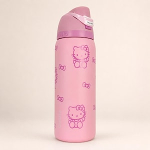 K&ouml;nnte beinhalten: Eine hellrosa Owala-Trinkflasche mit einem sich wiederholenden Muster aus Hello Kitty-Figuren und kleinen Schleifen in einem dunkleren Rosaton. Die Flasche hat einen rosa Deckel mit Klappmechanismus und einem wei&szlig;en Etikett mit der Aufschrift Lift to Sip.
