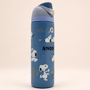 May include: A blue Owala water bottle featuring a Snoopy graphic print with the text "Spare Time" and "SNOOP". The bottle has a dark blue lid with a light blue collar, a carry loop, and a push-button mechanism for the spout, showcasing various Snoopy poses.