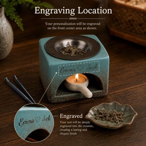 May include: A square teal ceramic oil burner with a dark brown base and a metal top dish containing dried herbs. A small white candle holder with a lit tea light sits inside the opening. The front features the engraved text Emma heart Jack.