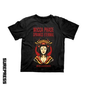 May include: A black short-sleeve t-shirt featuring the red text WICCA PHASE SPRINGS ETERNAL above a graphic illustration of a person with traditional hair ornaments and makeup, set against a red circle. The text #HELLVERSION appears at the bottom.