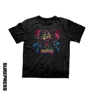 May include: A black short-sleeve t-shirt featuring a graphic print of a snarling, dark-furred creature with glowing yellow eyes and sharp teeth. The text "Miss May I" is printed in a stylized font below the creature, with blue clawed hands.