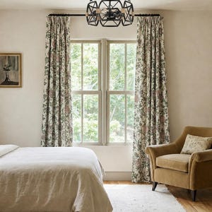 May include: A black metal chandelier featuring a geometric cage design with rope-wrapped accents, suspended by a central rod and chain assembly, housing multiple light bulbs within its open frame structure, centered above a window.