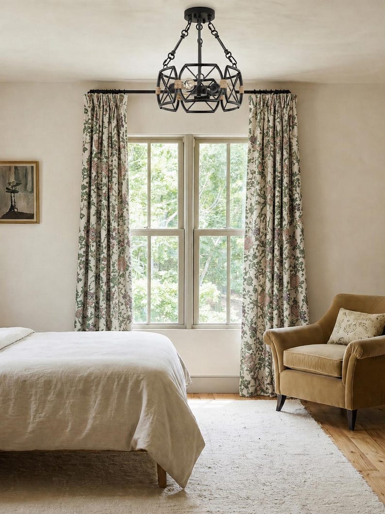 May include: A black metal chandelier featuring a geometric cage design with rope-wrapped accents, suspended by a central rod and chain assembly, housing multiple light bulbs within its open frame structure, centered above a window.