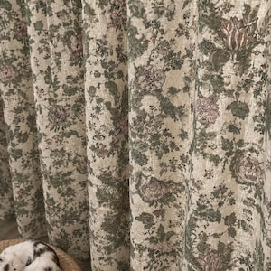 May include: Floor-length curtains featuring a cream-colored base fabric with an intricate floral pattern in shades of sage green and muted pink. The fabric has a textured, woven appearance with vertical folds creating deep, rhythmic pleats.