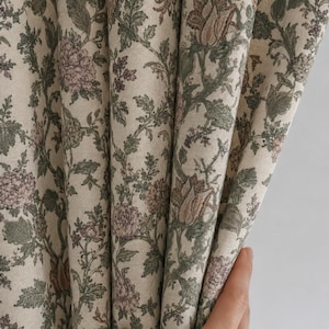 May include: A curtain panel featuring a dense botanical print on a light beige background. The fabric displays intricate floral patterns in muted shades of sage green, dusty rose, and brown, with detailed leaves and blossoms covering the surface.