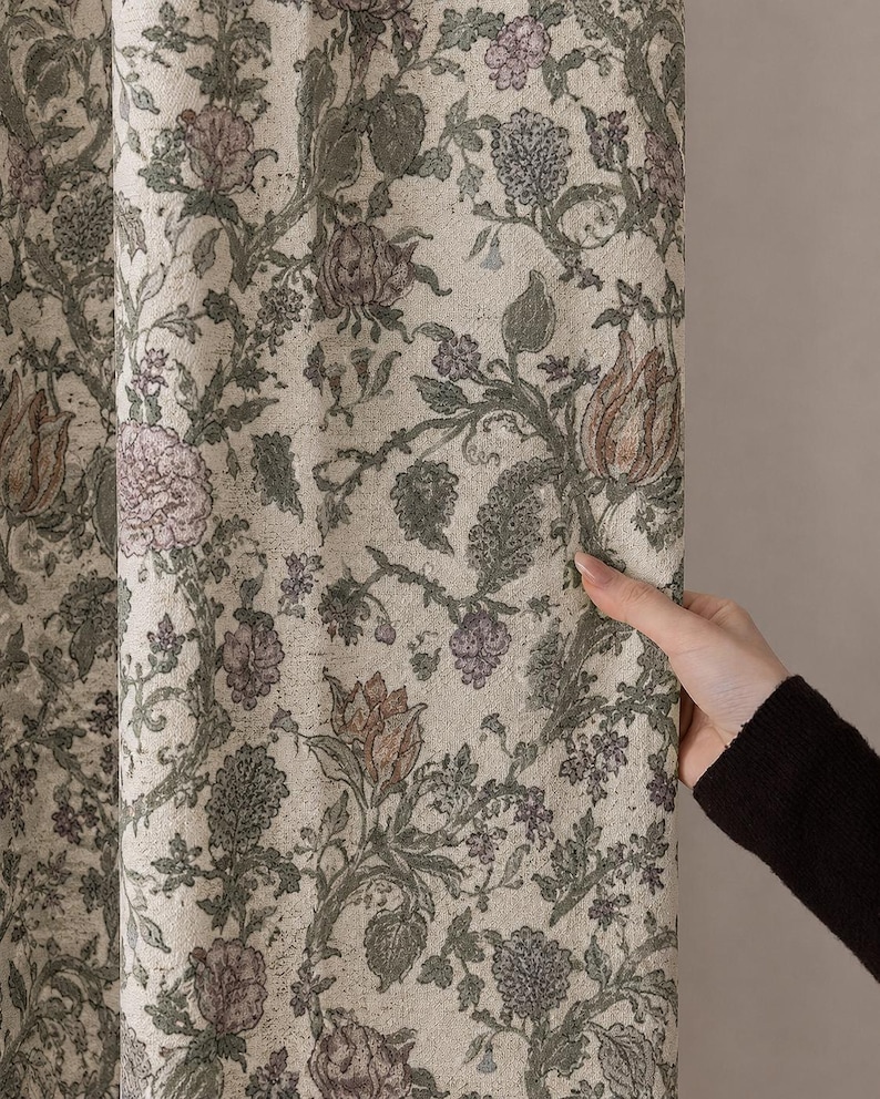 May include: A fabric curtain featuring a dense, intricate botanical pattern with muted green vines, sage leaves, and soft mauve floral blossoms set against a light cream-colored background. The textile displays a textured, woven appearance.