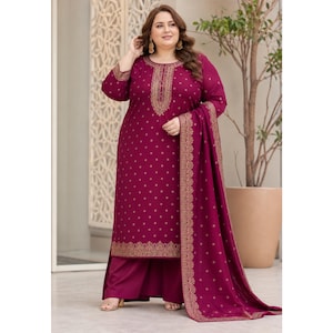 May include: A plum-colored, long-sleeved salwar kameez suit with gold embroidery. The suit features a tunic top, wide-leg pants, and a matching scarf. The embroidery is concentrated around the neckline, cuffs, and hem, and the fabric has a subtle dotted pattern.