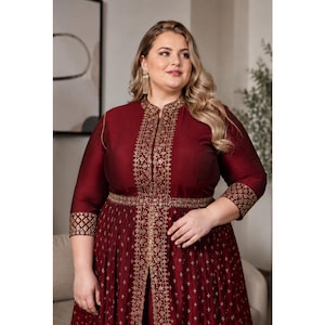May include: A deep maroon long-sleeved dress featuring a high neckline and a front slit. The garment is adorned with intricate gold embroidery along the centre placket, waist, and cuffs, complemented by a subtle gold cross-patterned print.