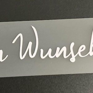Può includere: Un adesivo rettangolare smerigliato con le parole "Dein Wunschtext" in corsivo bianco. L'adesivo ha angoli arrotondati ed è posto su uno sfondo grigio scuro.