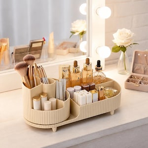 May include: A beige plastic cosmetic organiser with a ribbed exterior design, featuring a circular rotating section for makeup brushes and a rectangular compartment for skincare bottles, lipsticks, and small beauty items on a vanity surface.