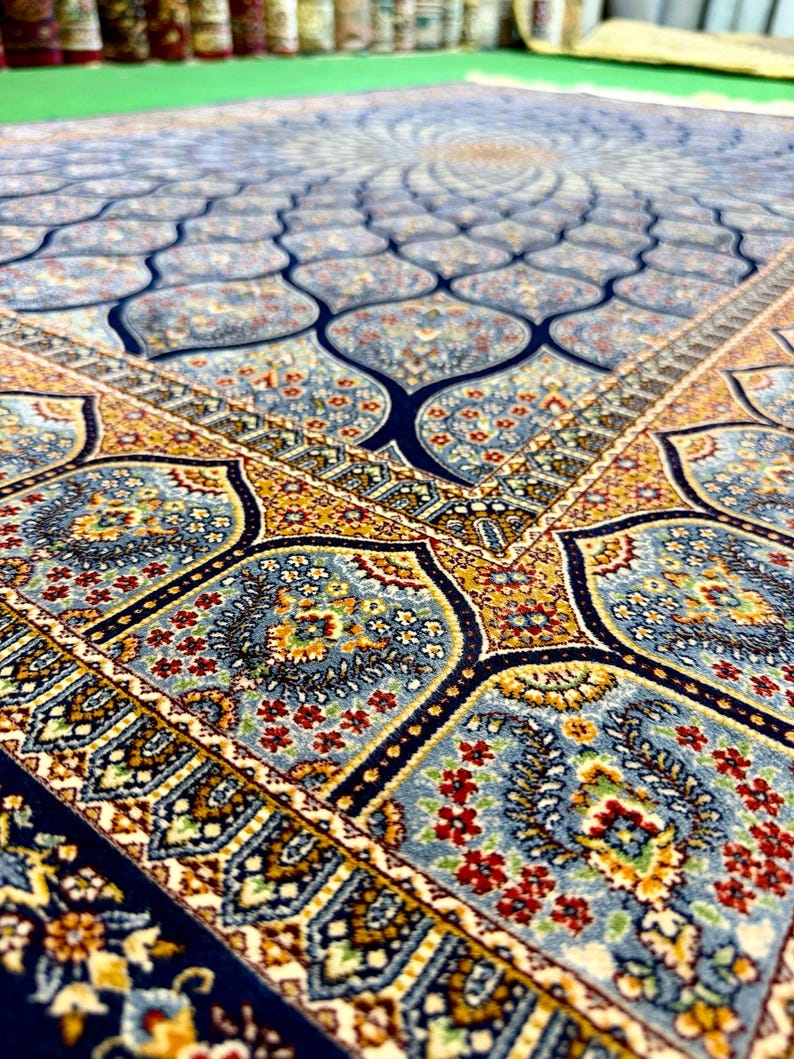 Puede incluir: Una alfombra rectangular con un complejo patr&oacute;n repetitivo de motivos florales en azul, dorado y rojo. El dise&ntilde;o incluye formas festoneadas interconectadas y bordes intrincados con elementos bot&aacute;nicos detallados en una textura densa.