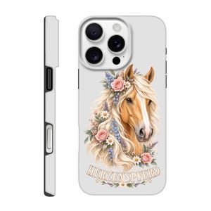 Könnte beinhalten: Eine hellgraue Smartphone-Hülle mit einem braunen Pferd, dessen lange blonde Mähne mit rosa Rosen, weißen Gänseblümchen und blauen Blumen geschmückt ist. Unter dem Pferd steht der Schriftzug HERZENSPFERD in einer dekorativen Serifenschrift.