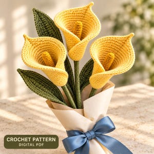Könnte beinhalten: Ein Strauß aus drei gehäkelten gelben Calla-Lilien mit dunkelgrünen Blättern und Stielen, eingewickelt in hellbeiges Papier und mit einem blauen Satinband gebunden. Das Bild enthält den Text CROCHET PATTERN DIGITAL PDF.