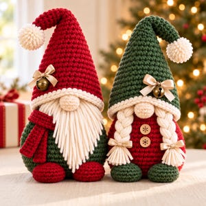 May include: Two crochet gnomes featuring festive colors. The left gnome has a red hat with a cream pom-pom, a long white beard, and a red scarf. The right gnome has a green hat with a cream pom-pom, two white braided pigtails, and two wooden buttons.
