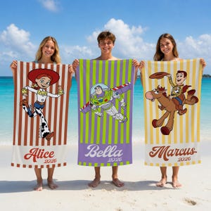 May include: Three rectangular beach towels featuring Toy Story characters. The left towel has brown stripes and Jessie, the center has green and purple stripes with Buzz Lightyear, and the right has yellow stripes with Woody on Bullseye. Names and 2026 are printed.