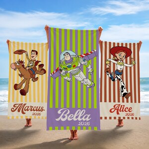 May include: Three rectangular beach towels featuring Toy Story characters. The left towel is yellow with vertical stripes, Woody on Bullseye, and the name Marcus 2026. The center is purple and green with Buzz Lightyear and Bella 2026. The right is brown with Jessie and Alice 2026.