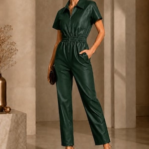May include: A dark forest green short-sleeved jumpsuit featuring a collared neckline, a full-length front zipper, an elasticized waist, and straight-leg trousers. The garment has a smooth, leather-like finish and includes side pockets.