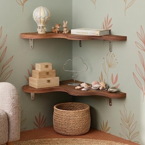 May include: Two dark wood corner shelves with wavy front edges, mounted with silver metal brackets. The top shelf holds a hot air balloon figurine, two small animal figures, and a book. The bottom shelf holds three wooden boxes, a wire cloud sculpture, and seashells.