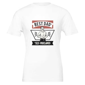 May include: White t-shirt with a graphic design. The design features the text "BEST DAD *SELF-PROCLAIMED" in a red and black banner. The graphic includes a cartoon illustration of a man laughing.