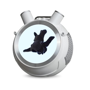 May include: A white and silver device with two cylindrical projections on top and a circular screen displaying a black, abstract shape. The device has a handle and a textured side panel.