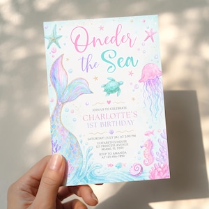 Puede incluir: Una tarjeta de invitación rectangular con ilustraciones en acuarela de una cola de sirena, tortuga marina, medusa, caballito de mar y estrellas de mar. El texto dice Oneder the Sea, Join us to celebrate Charlotte's 1st birthday, Saturday July 24 at 2:00 PM, Elizabeth's House, 123 Princess Avenue, Miami, FL 33101, RSVP to Amanda at 123-456-7890.