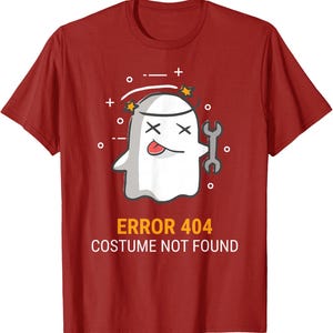 Op de afbeelding: Een rood T-shirt met korte mouwen en een afbeelding van een witte geest met X-vormige ogen, een uitgestoken tong en een moersleutel. Boven de geest staan kleine sterren en symbolen. Onder de afbeelding staat de tekst ERROR 404 COSTUME NOT FOUND.