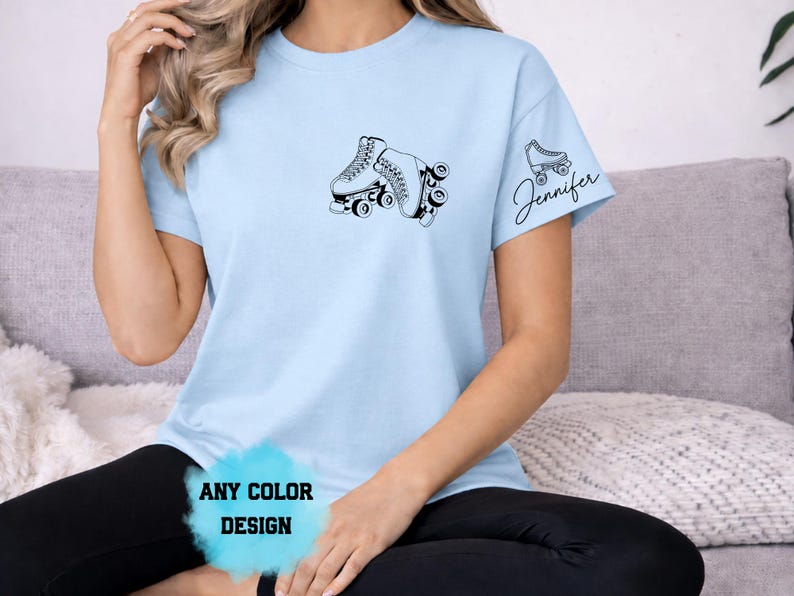 May include: Light blue t-shirt featuring a black graphic of roller skates. The shirt has the text "Jennifer" on the sleeve. The text "ANY COLOR DESIGN" is also visible on the shirt.
