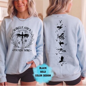 May include: Light blue sweatshirt with a black dragon graphic on the front and back. The front features the text "WINGLEADER" and "FOURTH WING". The back has a vertical design of black dragons and stars.