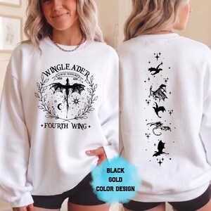 May include: White sweatshirt with a black and gold design. The front features a dragon graphic with the text "WINGLEADER" and "FOURTH WING". The back displays a series of black dragon silhouettes and stars. The design is labeled "BLACK GOLD COLOR DESIGN".
