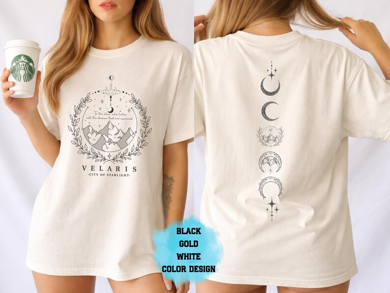 Pode incluir: Camiseta creme com um gr&aacute;fico frontal com montanhas, texto e um design de coroa de louros. A parte de tr&aacute;s da camiseta exibe um gr&aacute;fico vertical de fases da lua. O texto na frente diz "VELARIS - CITY OF STARLIGHT".
