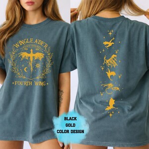 Op de afbeelding: Tealkleurig T-shirt met gouden grafische ontwerpen. De voorkant heeft een gevleugeld wezenontwerp met de tekst "WINGLEADER" en "FOURTH WING". De achterkant toont verschillende vliegende drakenillustraties. Het shirt is een zwart en goud kleurontwerp.