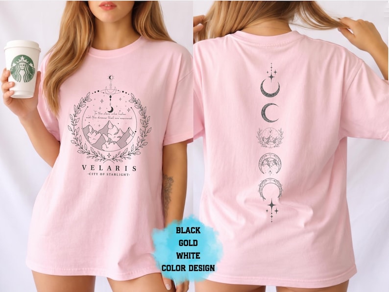 Pode incluir: Camiseta rosa claro com um design gr&aacute;fico na frente e atr&aacute;s. A frente apresenta uma paisagem montanhosa dentro de uma moldura circular com o texto "VELARIS - CITY OF STARLIGHT". A parte de tr&aacute;s exibe uma disposi&ccedil;&atilde;o vertical das fases da lua. O texto "BLACK GOLD WHITE COLOR DESIGN" tamb&eacute;m &eacute; vis&iacute;vel.