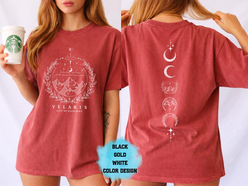 Pode incluir: Camiseta vermelho-alaranjada com um gr&aacute;fico branco na frente com montanhas, uma lua crescente e o texto "VELARIS - CITY OF STARLIGHT". A parte de tr&aacute;s da camisa tem um desenho branco de fases da lua e estrelas.