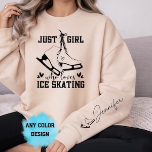 Może przedstawiać: Beżowa bluza z napisem "JUST A GIRL who loves ICE SKATING" i grafiką łyżwy. Na rękawie widnieje imię "Jennifer" pisane kursywą oraz mała grafika łyżwy.