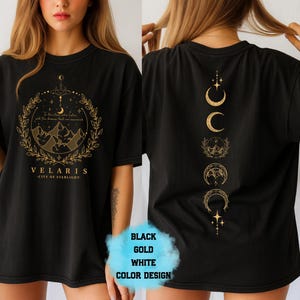 Pode incluir: Camiseta preta com um design dourado com montanhas, estrelas e o texto "VELARIS - CITY OF STARLIGHT". A parte de tr&aacute;s da camisa exibe um design vertical de luas e estrelas. A camisa &eacute; um design de cores preto, dourado e branco.