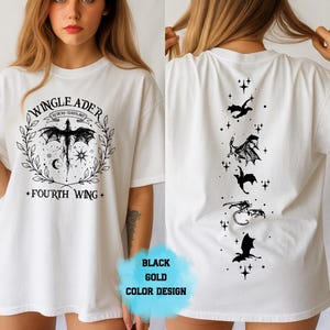 Op de afbeelding: Wit T-shirt met een zwarte drakenafbeelding en de tekst "WINGLEADER" en "FOURTH WING". De achterkant van het shirt heeft een verticale lijn van drakensilhouetten en sterren. Het ontwerp is in zwart en goud.