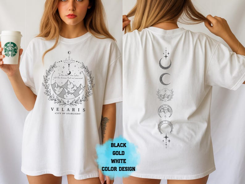 Pode incluir: Camiseta branca com um gr&aacute;fico frontal com montanhas, uma lua crescente e o texto "VELARIS - CITY OF STARLIGHT". A parte de tr&aacute;s da camisa exibe uma s&eacute;rie de fases da lua.