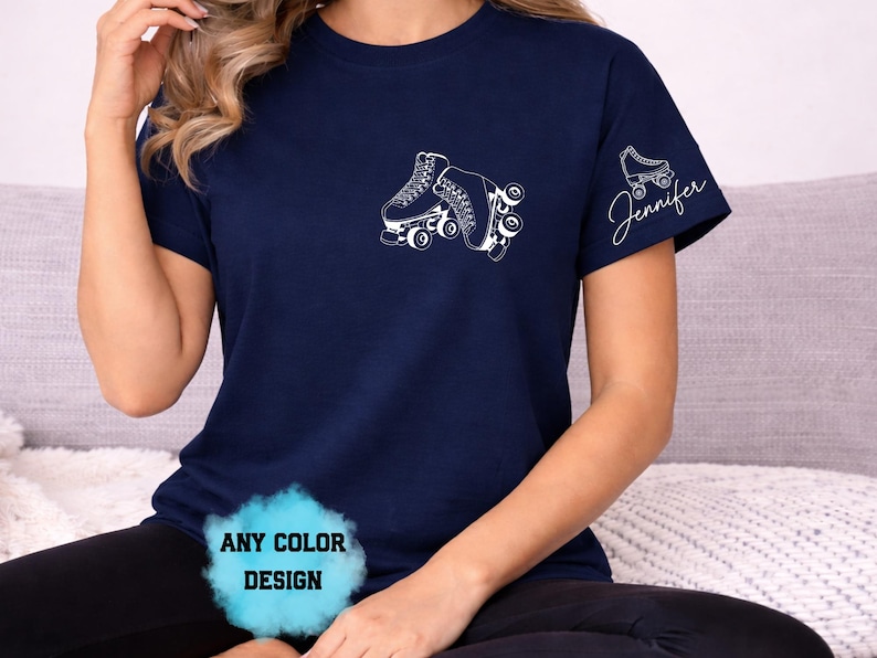 May include: Navy blue t-shirt with a white roller skate graphic on the front and a smaller roller skate design with the name "Jennifer" on the sleeve. The shirt has a crew neck and short sleeves. The text "ANY COLOR DESIGN" is also visible.