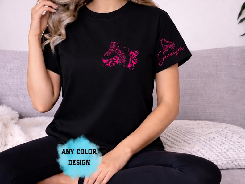 May include: Black t-shirt with a pink roller skate graphic on the front and a smaller skate and the name "Jennifer" on the sleeve. The text "ANY COLOR DESIGN" is also visible. The shirt is made of a soft material.