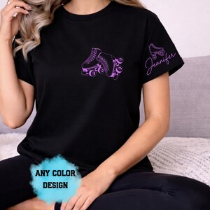 May include: Black t-shirt featuring a purple roller skate design on the front and sleeve. The sleeve has the name "Jennifer" in a script font. The shirt also has the text "ANY COLOR DESIGN" in a blue cloud.