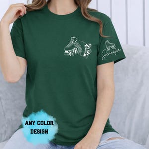 May include: Dark green t-shirt featuring a white roller skate design on the chest and a smaller skate with the name "Jennifer" on the sleeve. The shirt also has the text "ANY COLOR DESIGN" in a blue bubble.