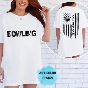 Może przedstawiać: Biały t-shirt z czarnym napisem BOWLING z przodu. Z tyłu znajduje się czarna grafika przedstawiająca kulę do kręgli i kręgle ułożone na wzór amerykańskiej flagi, z wyrazem CUSTOM wkomponowanym pionowo w pasy wzoru.