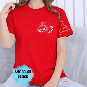 May include: Red t-shirt with a white roller skate graphic on the chest and a smaller skate with the name "Jennifer" on the sleeve. The shirt also has the text "ANY COLOR DESIGN" in a blue cloud.