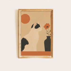 以下が含まれることがあります： 黒と白の猫が横向きに座り、オレンジ色の花が一輪入った黒い花瓶の横にいる様子を描いた額入りアートプリント。背景は無地のベージュ色で、左上隅には太陽を表す大きなオレンジ色の円が描かれています。