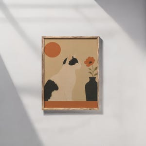 以下が含まれることがあります： 黒と白の猫が横向きに座り、オレンジ色の花が一輪入った黒い花瓶の隣にいる様子を描いた額入りアートプリント。背景は落ち着いたベージュ色で、猫の上には太陽を表すオレンジ色の円が描かれています。